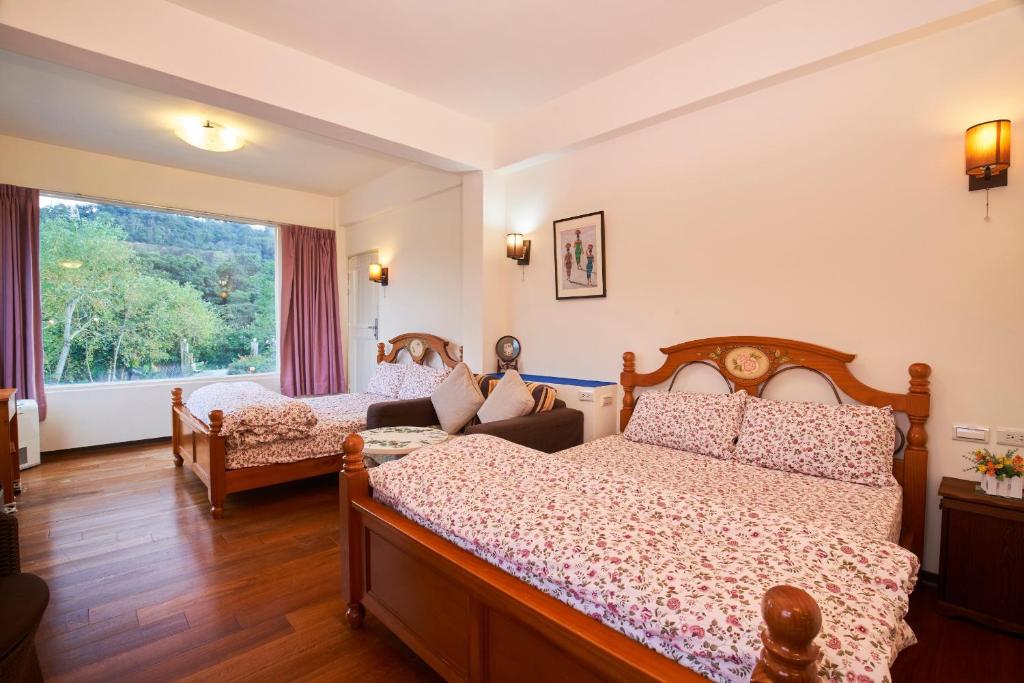 a bedroom with two beds and a couch and a window at Liang Chen Mei Jin B&amp;B in Shuangxi