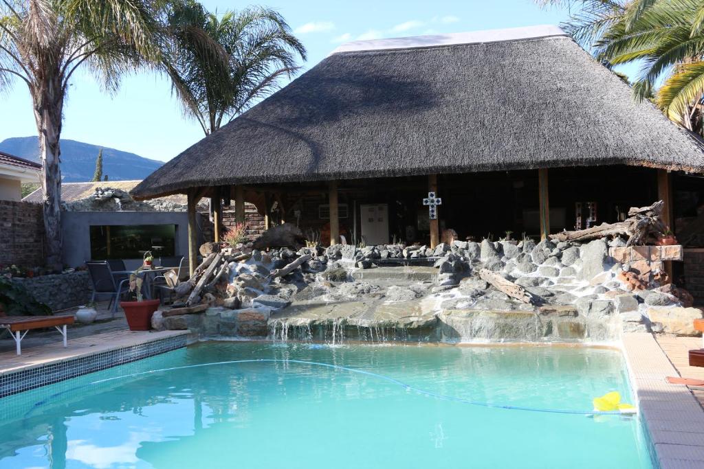 a swimming pool with a fountain in front of a building at Aan die Oewer Guesthouse in Graaff-Reinet