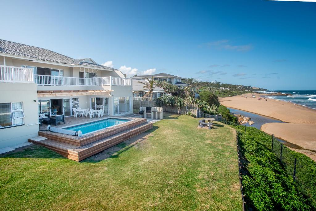 a view of a house with a swimming pool and the beach at Howela Beach House in Ballito