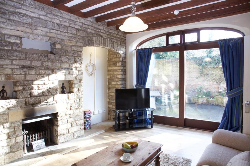 a living room with a stone fireplace and a television at The Coach House in Stamford