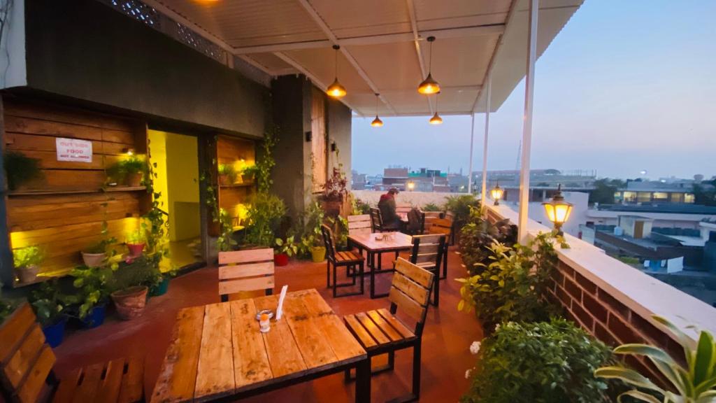 a restaurant with wooden tables and chairs on a balcony at Tuk Tuk Backpackers- Near Jaipur Train Station in Jaipur