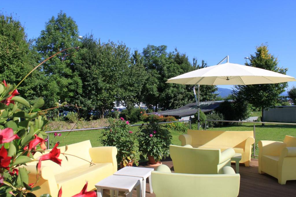a patio with yellow chairs and an umbrella at Airporthotel Salzburg - Hotel am Salzburg Airport in Salzburg