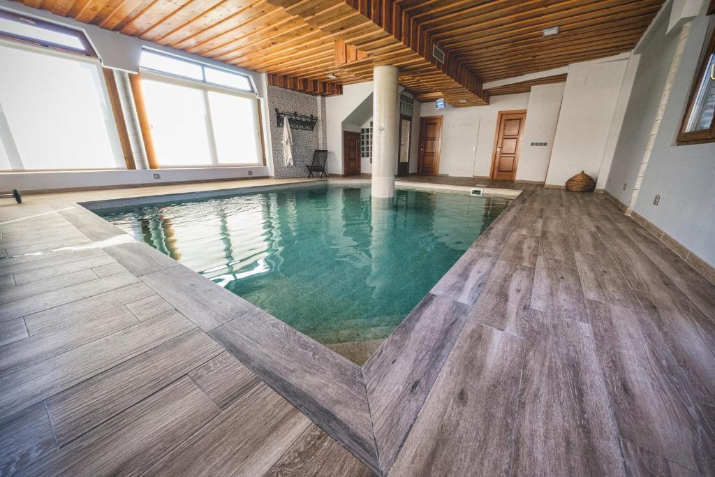 una gran piscina cubierta con suelo de madera y ventanas en Las Postas del Perionda, en Calzada de los Molinos