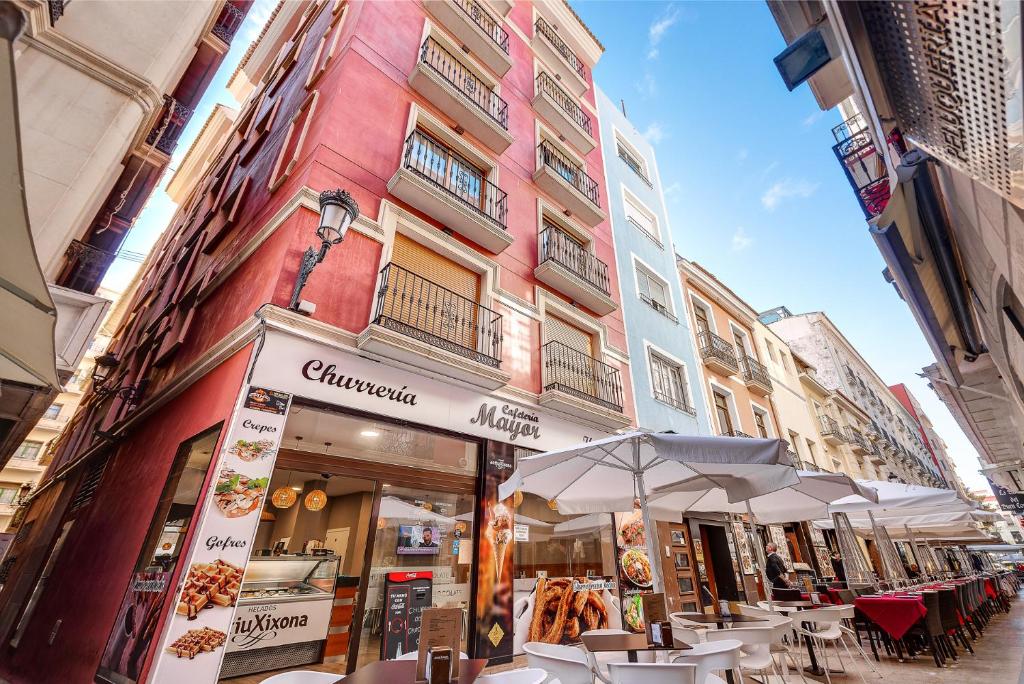 un restaurante con mesas y sombrillas frente a un edificio en Apartamentos Globus by Be Alicante, en Alicante