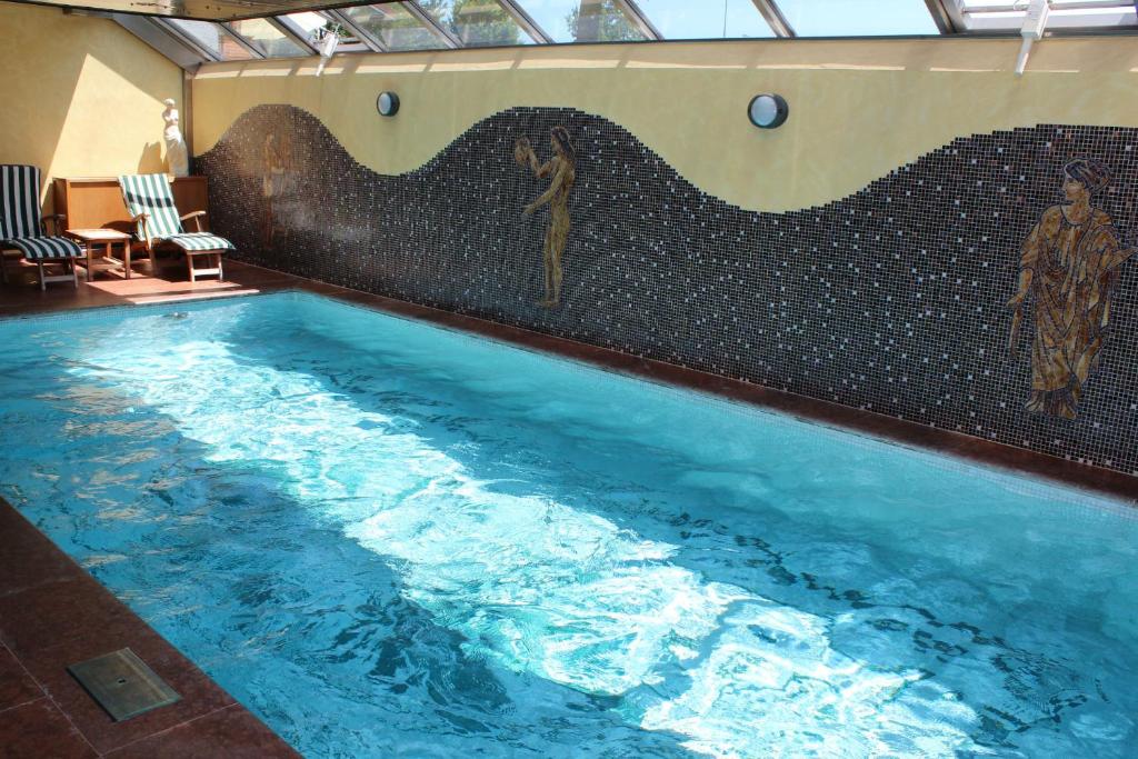 a large swimming pool with a mosaic wall at Airporthotel Salzburg - Hotel am Salzburg Airport in Salzburg
