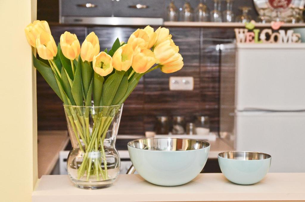 eine Vase gelber Tulpen auf einem Tisch mit zwei Schalen in der Unterkunft Happy apartman in Hajdúszoboszló