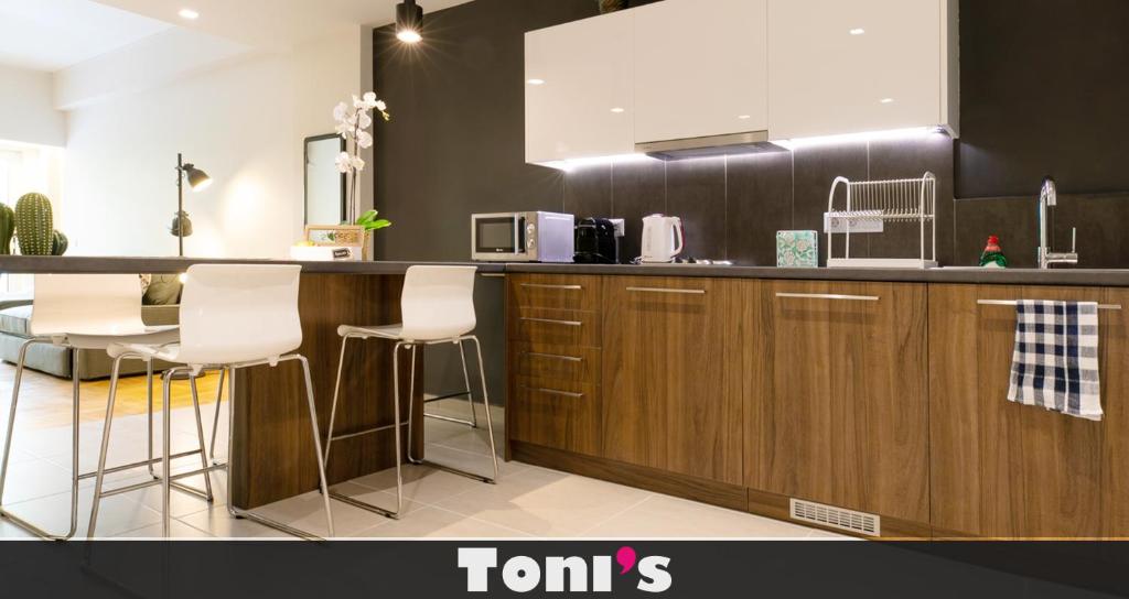 a kitchen with wooden cabinets and white stools at TONI'S Ironman's choice in Athens. Tony Stark in Athens