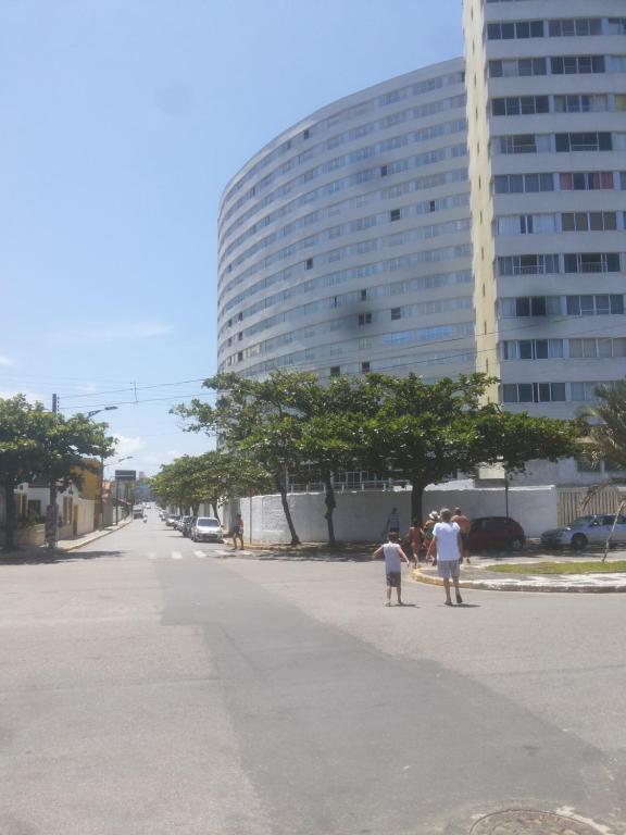 Menschen stehen auf einer Straße vor einem großen Gebäude in der Unterkunft Apartamento frente a praia in Peruíbe