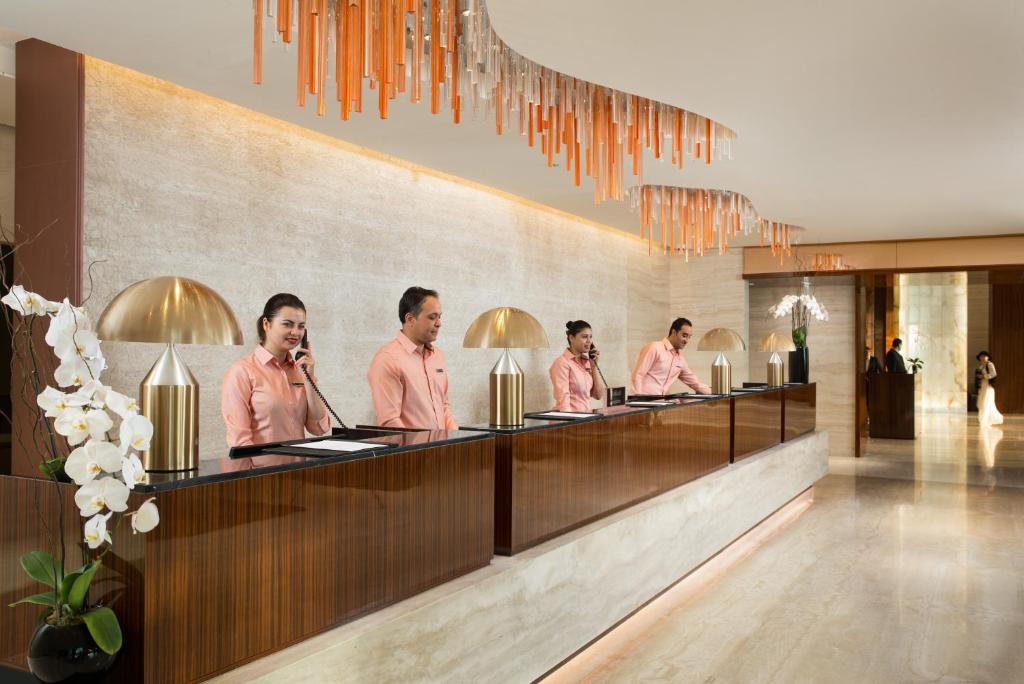 a group of men in pink shirts in a lobby at Millennium Place Barsha Heights Hotel in Dubai