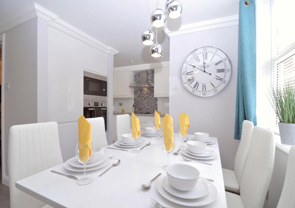 a dining room with a white table and a clock at Twenty Three B - 3 bedroomed apartment in Lee-on-the-Solent