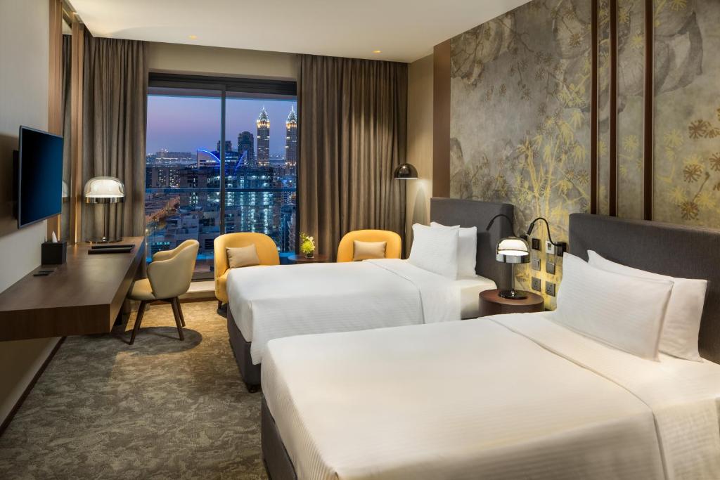 a hotel room with two beds and a window at Millennium Place Barsha Heights Hotel in Dubai