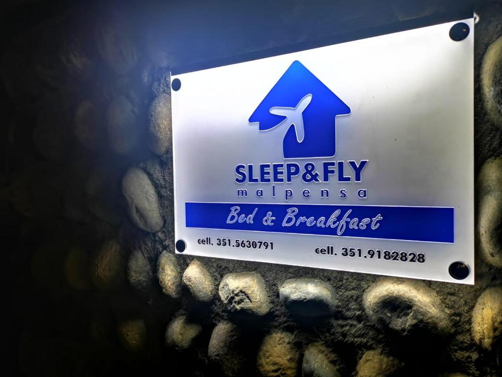 Una señal que dice dormir y volar pero y desayunar en Sleep & Fly Malpensa, en Case Nuove