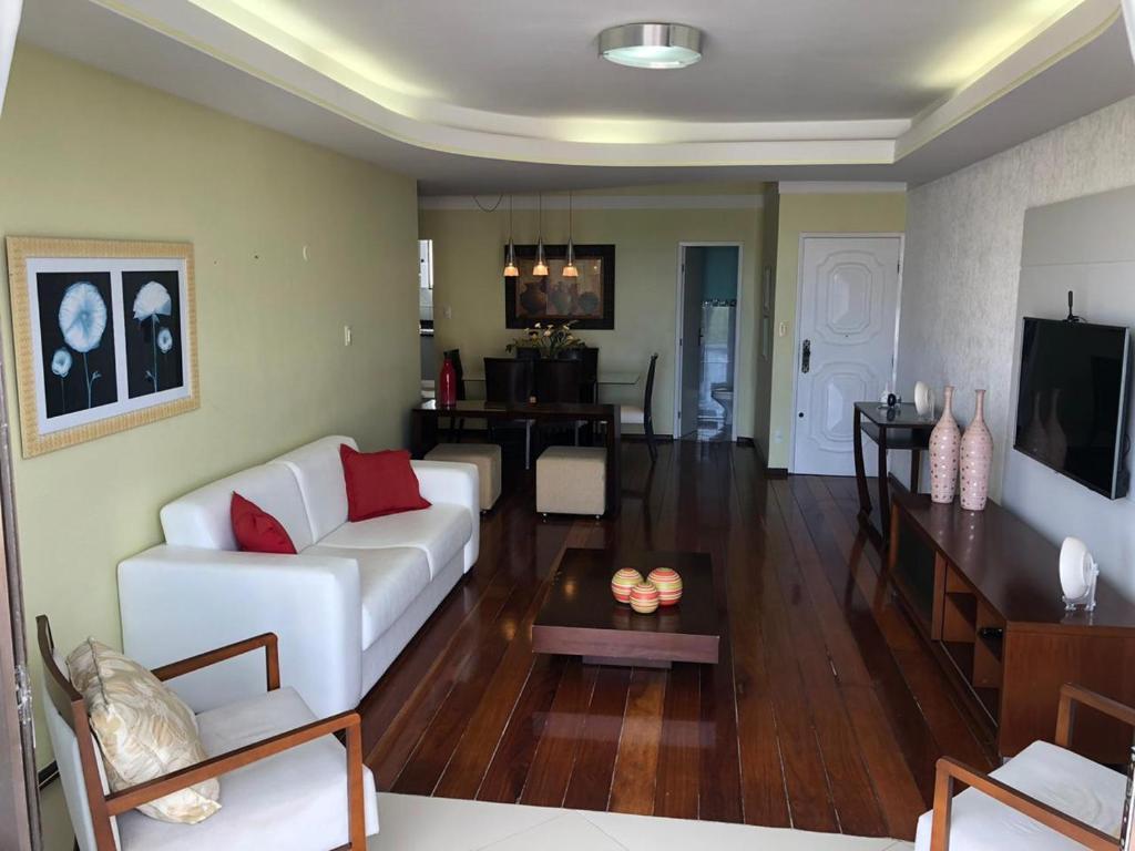 a living room with a white couch and a table at Apartamento amplo, arejado e confortável - Mínimo 3 noites in Ilhéus