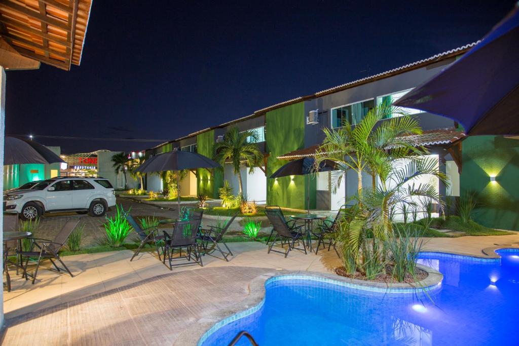 un patio del hotel con sillas y una piscina por la noche en Juazeiro Comfort Hotel, en Juazeiro do Norte