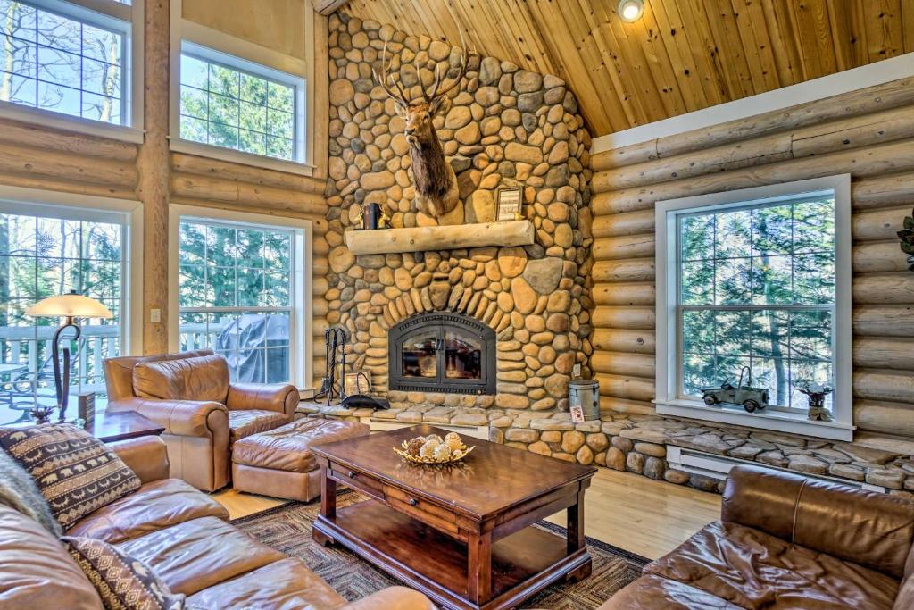 - un salon avec une cheminée en pierre dans une cabane en rondins dans l'établissement Secluded Log Cabin with Game Room and Forest Views, à Red Feather Lakes