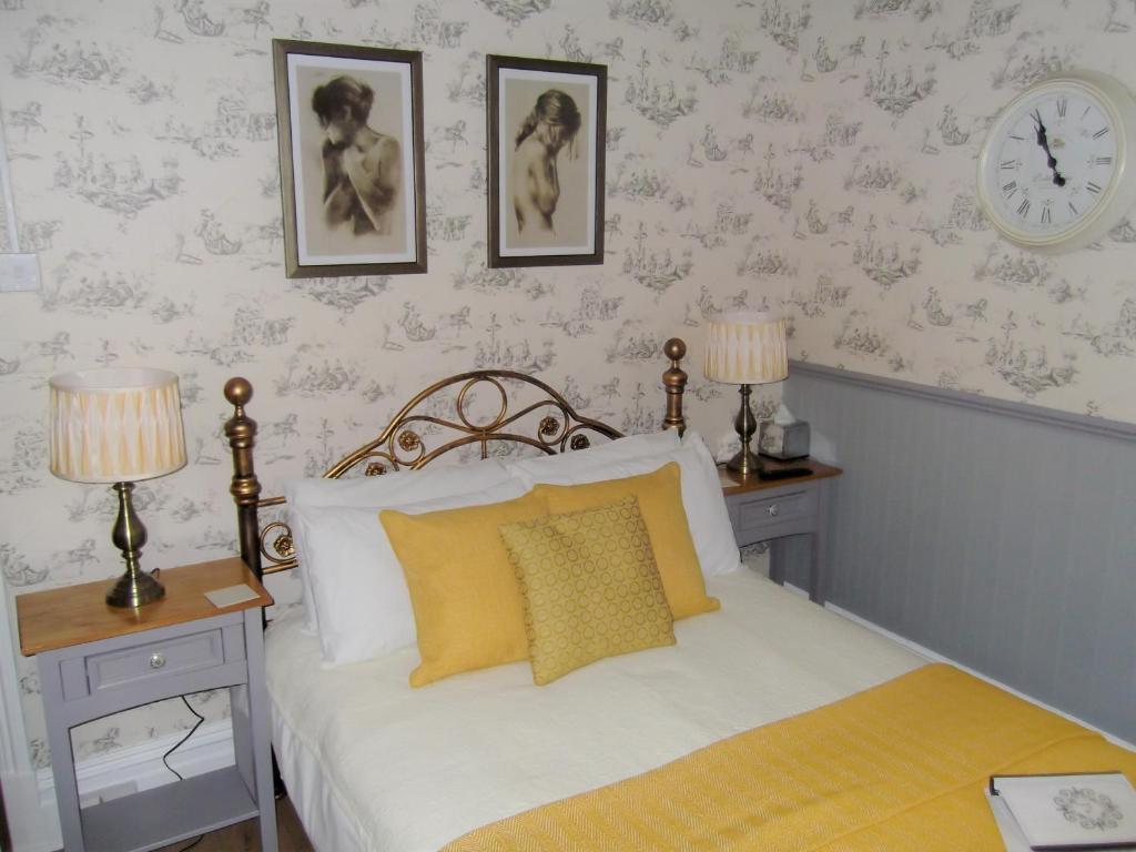 ブラックプールにあるJ's Mayfair Guest Houseのベッドルーム1室(ベッド1台、テーブル2台、時計付)