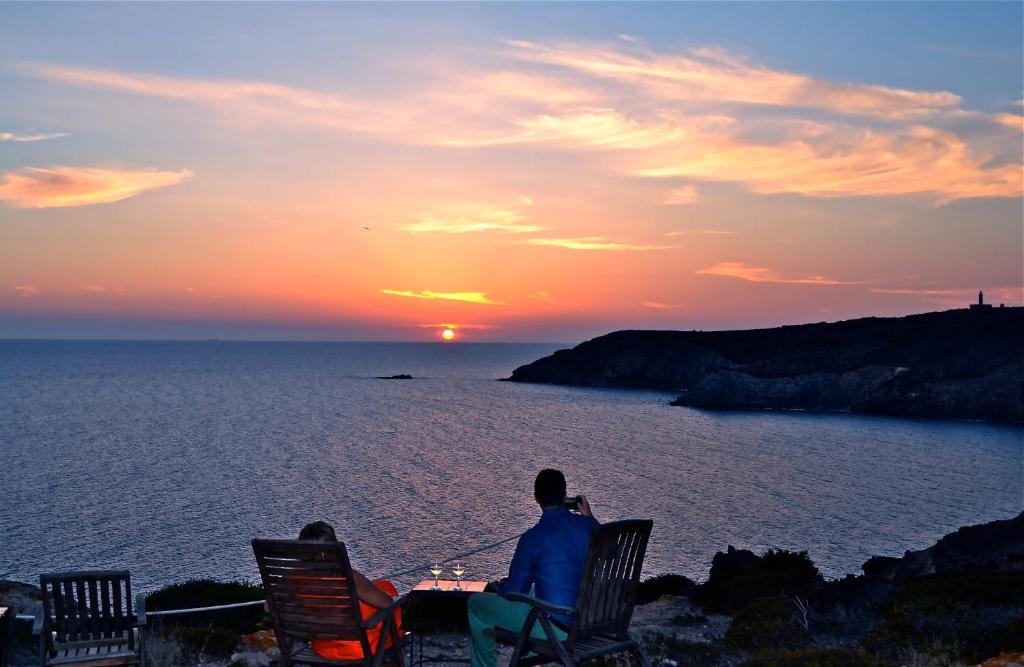 Due persone sedute a un tavolo a guardare il tramonto di Poecylia a Carloforte