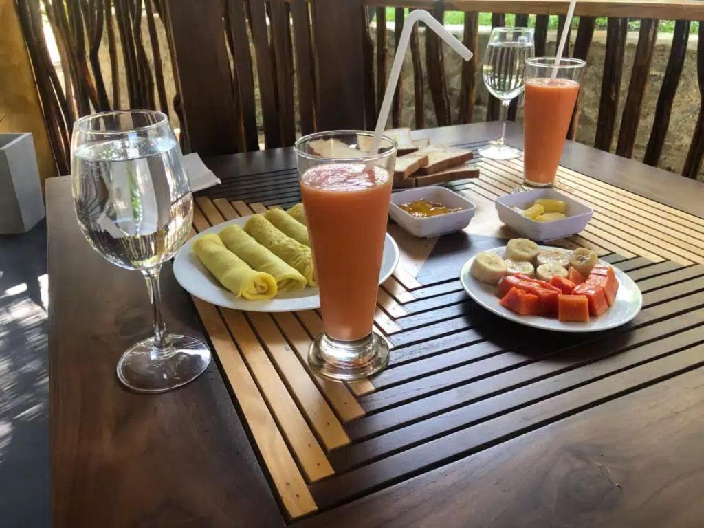 un tavolo con piatti di cibo e bicchieri di succo di skyresort a Tangalle