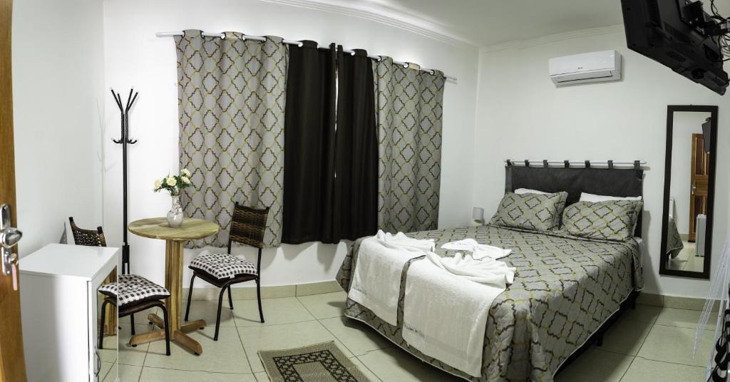 a bedroom with a bed and a table and chairs at Pousada Do Alto in Capitólio