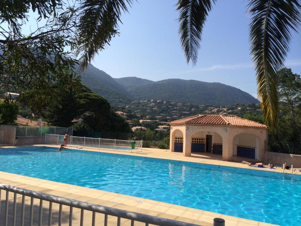 une piscine avec un kiosque et des montagnes en arrière-plan dans l'établissement Les Hauts de Bonporteau - nr 29, à Cavalaire-sur-Mer