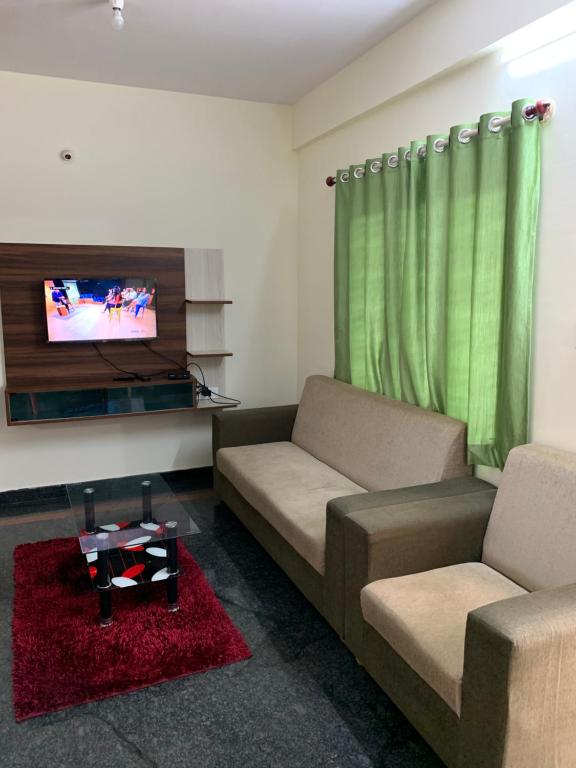 een woonkamer met 2 banken en een flatscreen-tv bij Haven Homes in Yelahanka