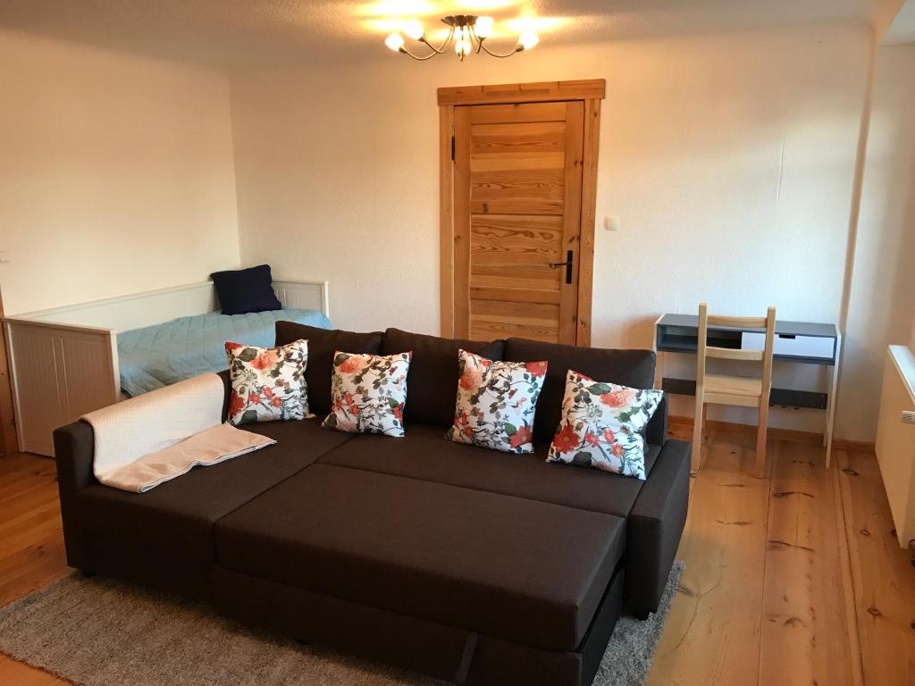 uma sala de estar com um sofá preto e uma cama em Sanierte möblierte Altbauwohnung am Waldrand für bis zu 6 Personen em Borkheide