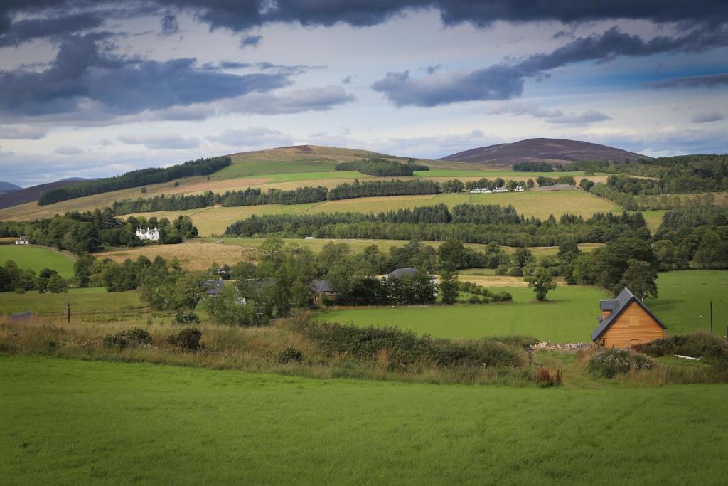 a green hillside with a house in a green field at Clova pod, Kilry eco pods in Blairgowrie