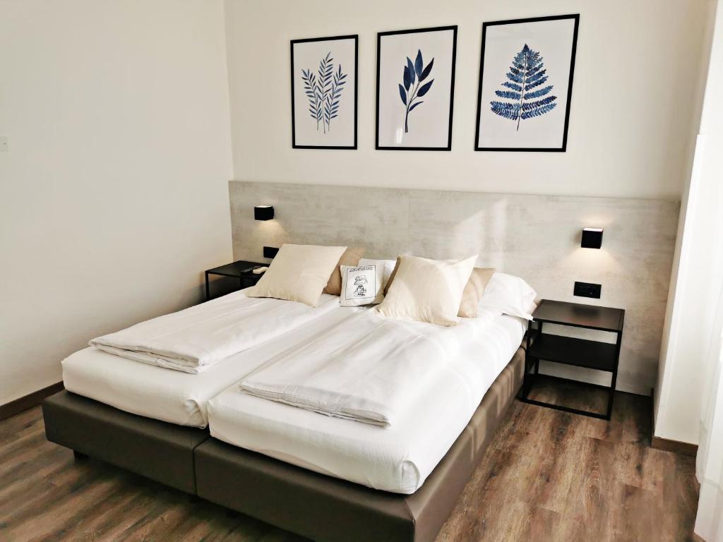 una camera da letto con un grande letto bianco con quattro immagini sul muro di Villa Paola B&B a Torbole