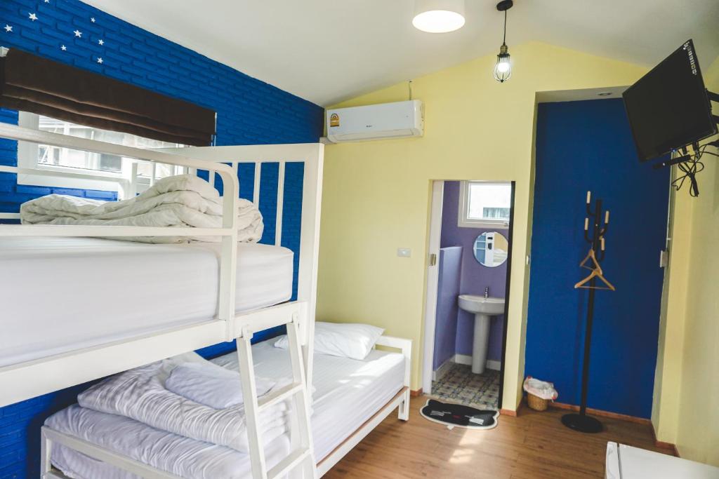 a bedroom with a bunk bed and a blue wall at Patoey House in Chon Buri