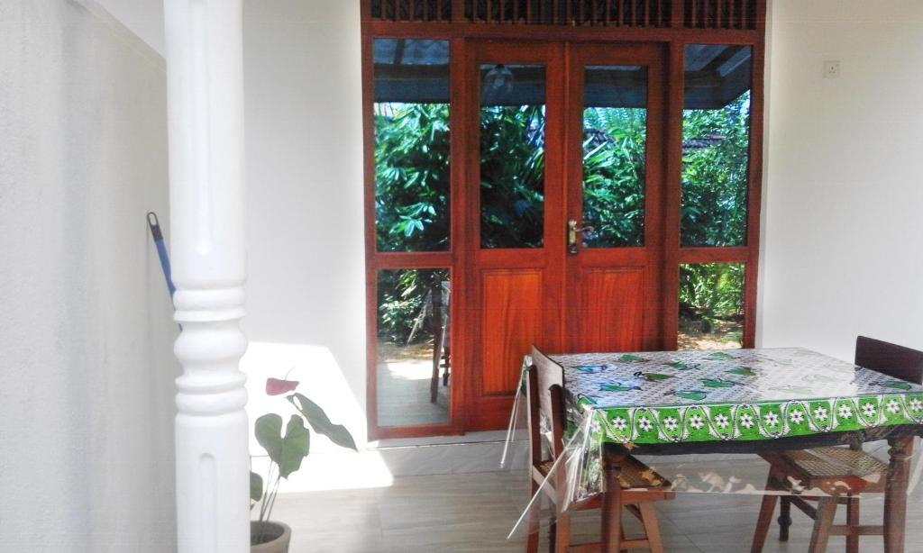 本托塔的住宿－Sisila Villa，一间设有桌子和红色门的用餐室