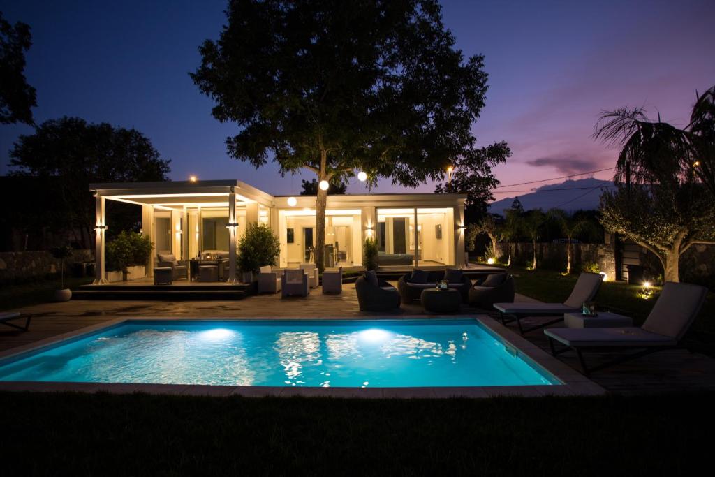una piscina frente a una casa por la noche en T Villa, en Calatabiano