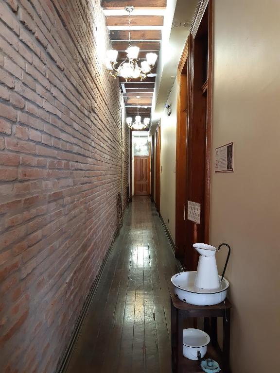a long hallway with a brick wall and a table at Hotel Reina Victoria Valparaíso in Valparaíso