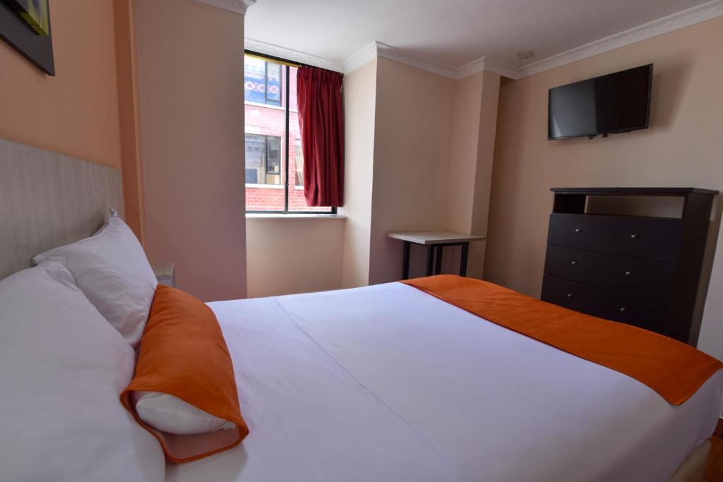 a bedroom with a white bed and a window at Hotel Mediterraneo Quito in Quito