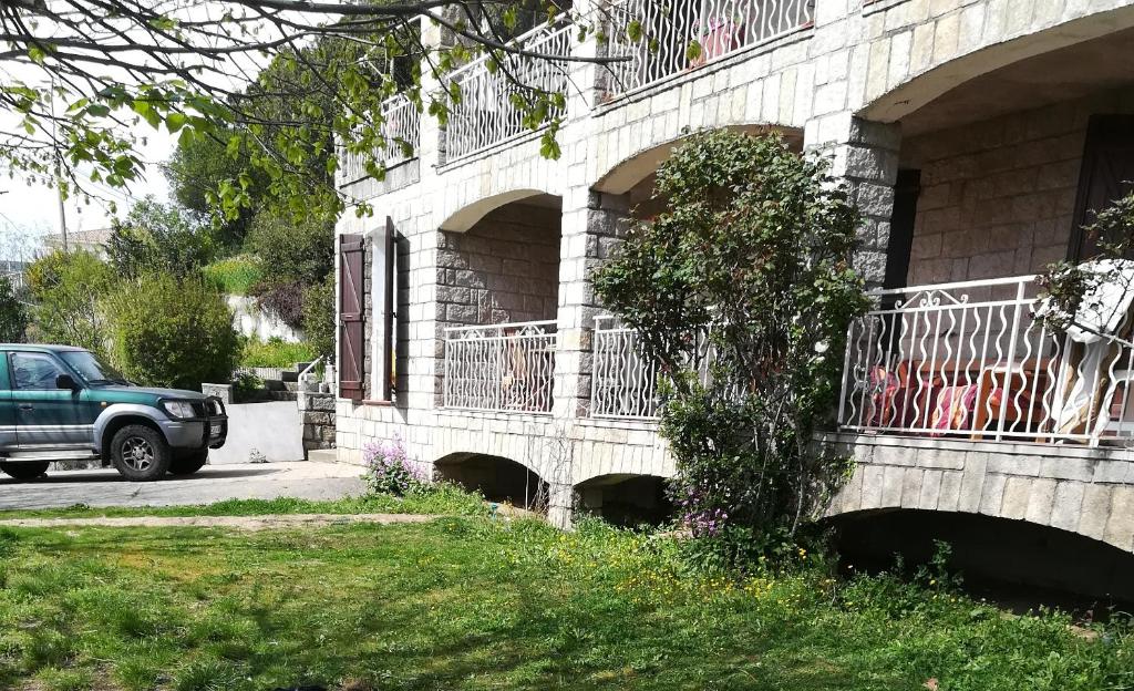 Casalabriva的住宿－Belle maison de charme ancien, vue mer et montagne，停在带阳台的建筑旁边的绿色卡车