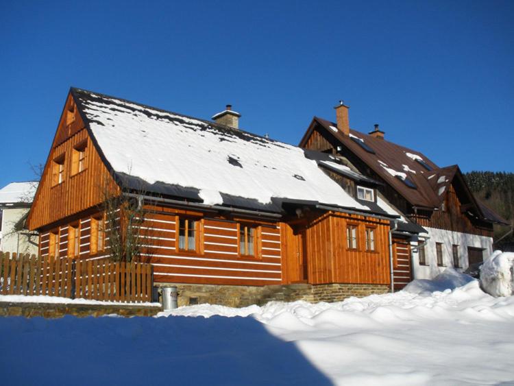a wooden house with snow on top of it at Chalupa 409 in Rokytnice nad Jizerou
