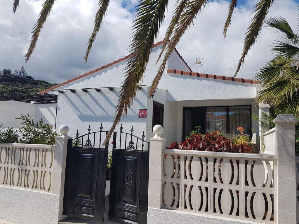 une maison blanche avec un portail et un palmier dans l'établissement Vivienda Vacacional la Palmera, à Los Cancajos