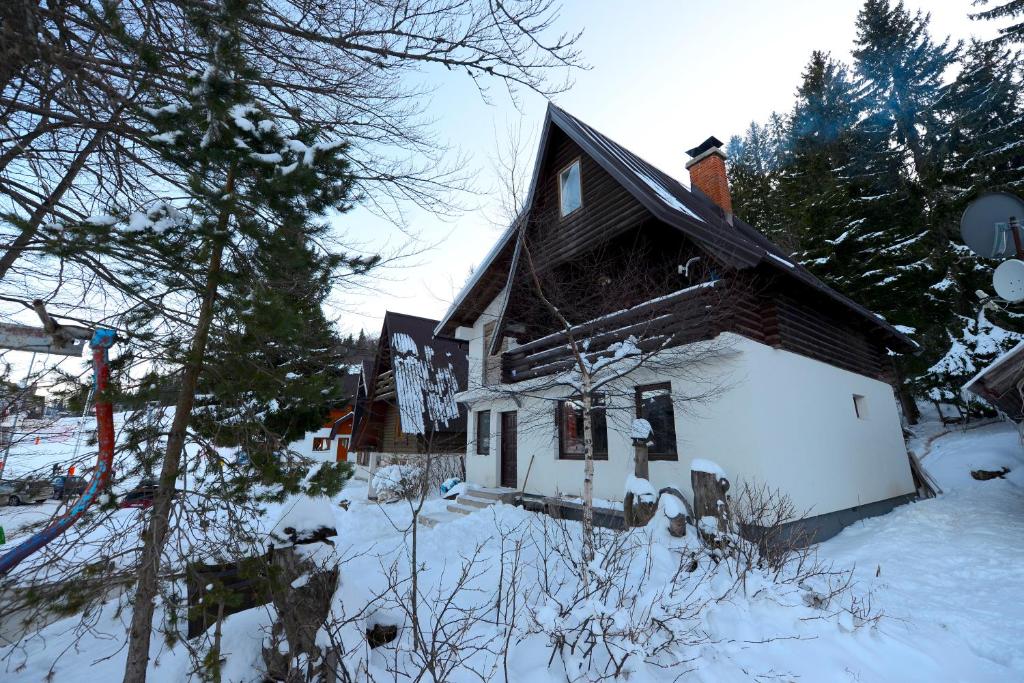 una casa está cubierta de nieve con árboles en Čarobna Kuća Jahorina en Jahorina
