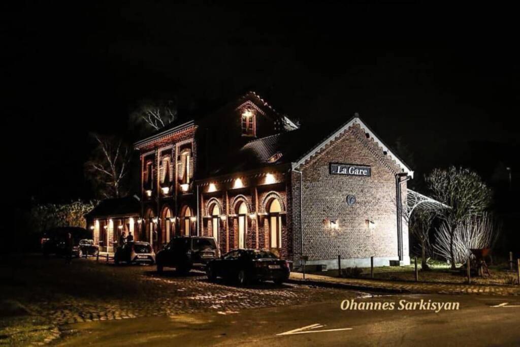 un edificio iluminado por la noche con coches aparcados delante en Appartement dans un bâtiment historique, en Thorembais-Saint-Trond