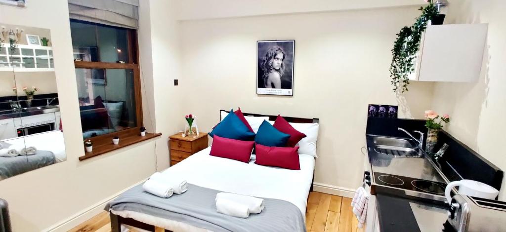 sypialnia z łóżkiem z czerwonymi i niebieskimi poduszkami w obiekcie White's Row Resident w Londynie