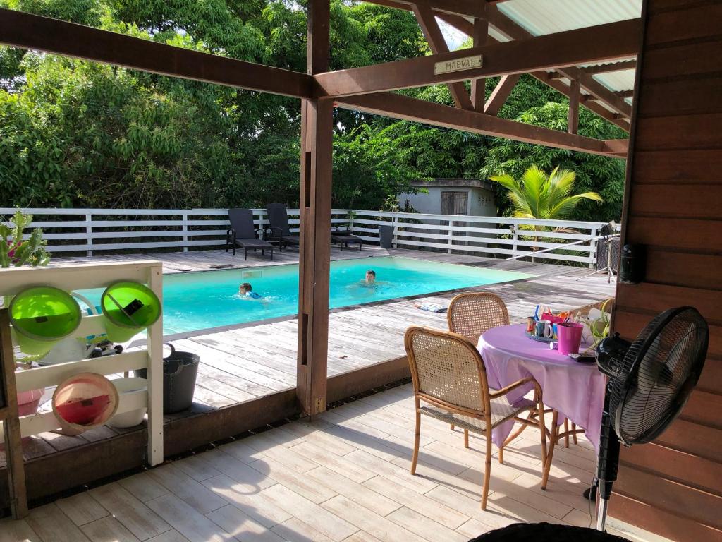 Matoury的住宿－VILLA LA CHAUMIERE Au calme et sans vis à vis，庭院设有游泳池、桌子和椅子。
