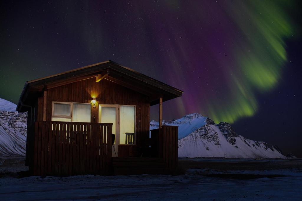 una cabaña con las luces del norte en el cielo en Aurora Cabins en Höfn