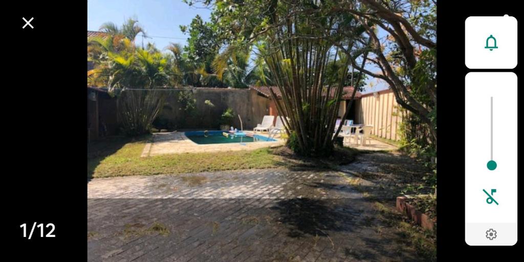 una foto de un patio trasero con una piscina y un árbol en Casa na Praia c/Piscina e Churrasqueira, en Itanhaém