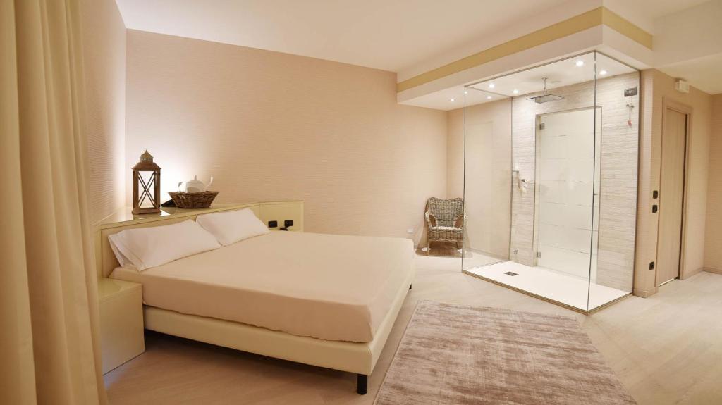 um quarto com uma cama branca e uma cabina de duche em vidro em Sweet Motel em Verdello