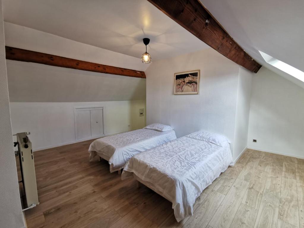 two beds in a room with white walls and wooden floors at Bondy chambre in Bondy