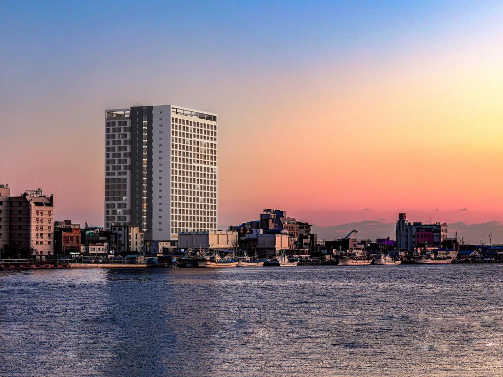 un perfil urbano con un edificio alto y el agua en World State Hotel Sokcho, en Sokcho