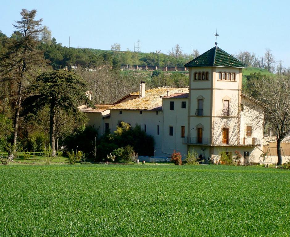 a building with a grass field in front of it at La Riera in Vic