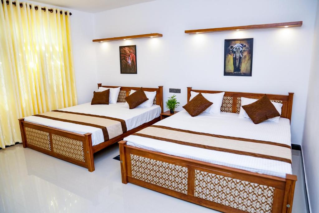 - 2 lits dans une chambre aux murs blancs dans l'établissement Seven Rich Villa, à Anurâdhapura