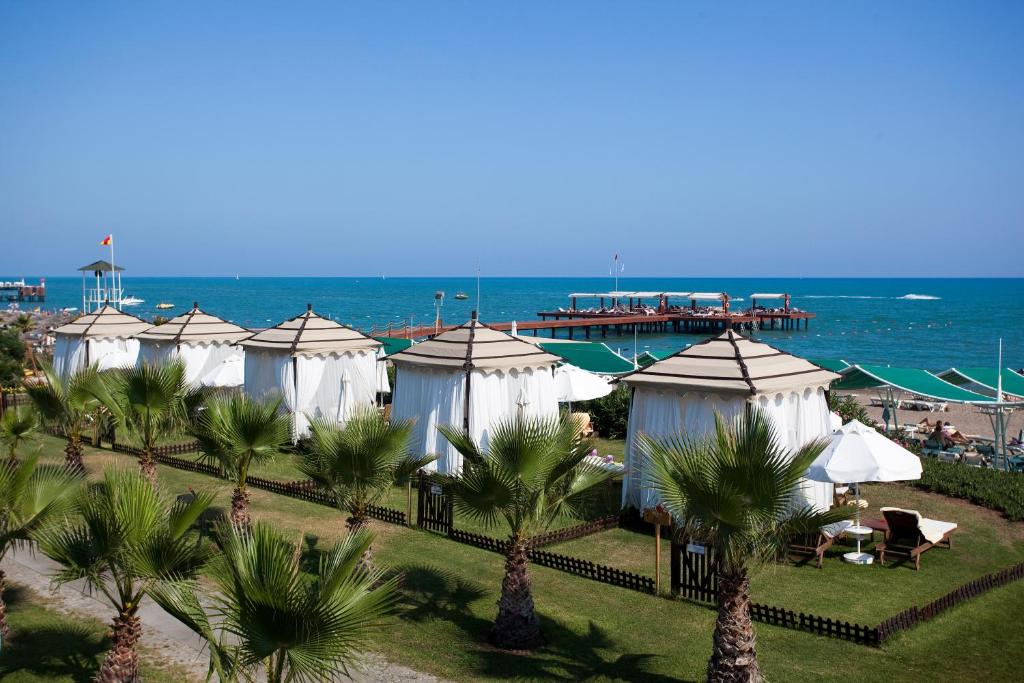 a row of white tents in front of the ocean at Limak Atlantis Deluxe Hotel Belek in Belek