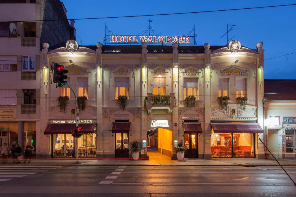 a hotel building on a city street at night at Hotel Waldinger in Osijek