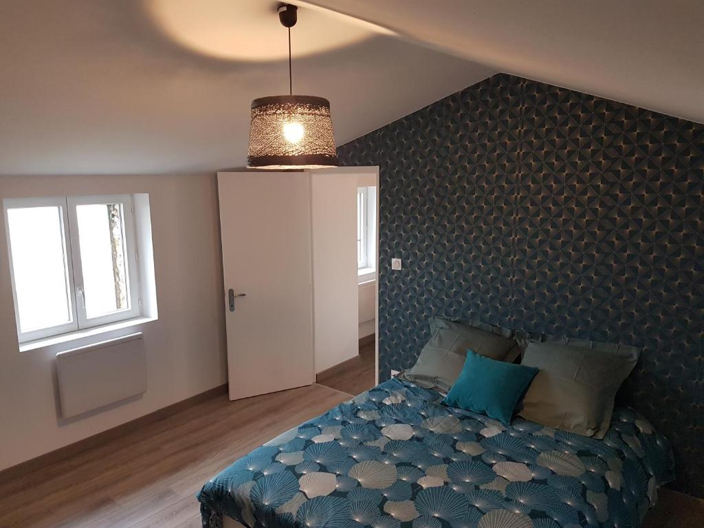 een slaapkamer met een bed met een blauw dekbed en een raam bij maison "Le Goéland" à deux pas des plages in Longeville-sur-Mer